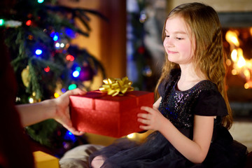 Happy little girl getting a Christmas gift from her mommy