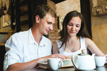 Young couple watching a family photo album. A man and his girl in white looking at the photo album and remember something between them
