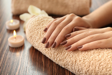 Female hands with brown manicure on towel - obrazy, fototapety, plakaty