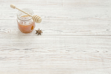 Fototapeta premium Jar of honey and stick with anise