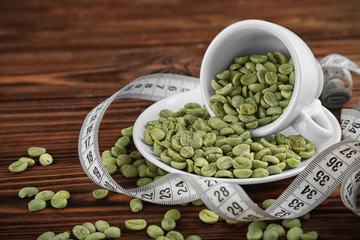 Cup of coffee with grains and measure tape on table