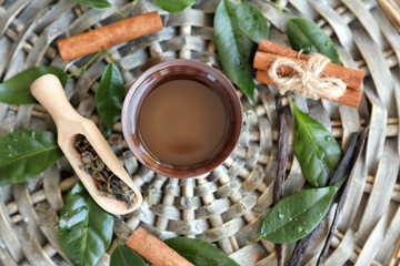 Bowl with tea oil on wicker mat, top view