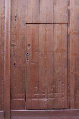 small brown wooden door cut out of much larger one