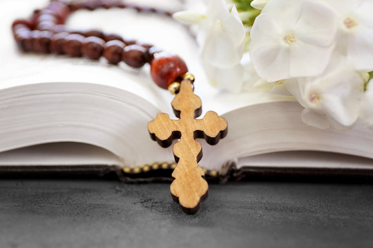 Wooden cross with flowers and Bible  on table closeup