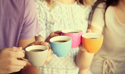 Group of people holding cups of coffee together