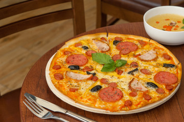 pizza on the kitchen table with a fork and soup
