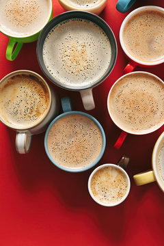 Cups of coffee on red background, top view