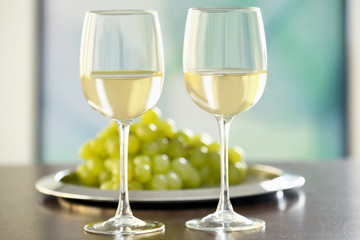 Glasses with white wine and grape on a table