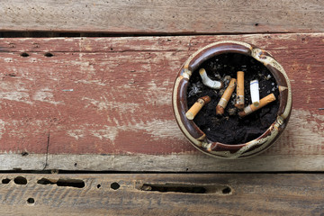 top view of cigarette butts in ashtray on wooden table background. over light