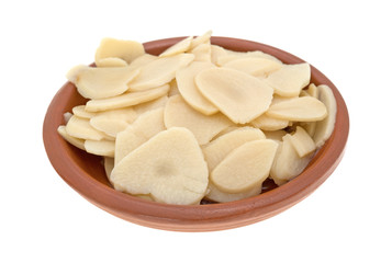 Sliced garlic in a bowl on a white background