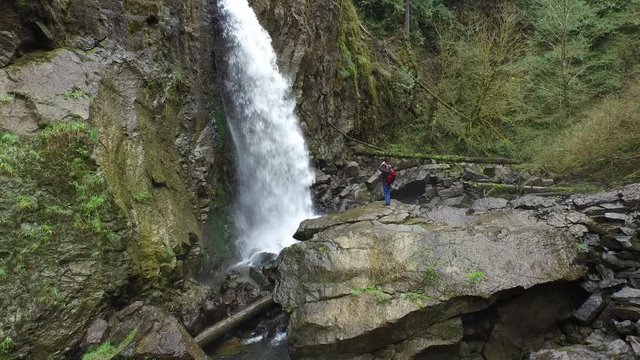 Aerial shot of backpacker taking photos of waterfall