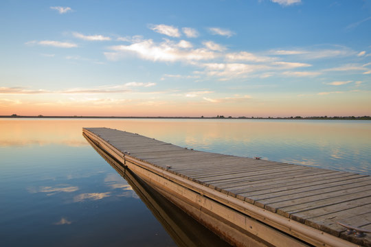  Fishing dock on a lake at sunrise with soft wispy clouds