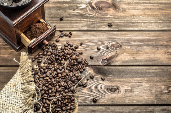 Coffee grinder and coffee beans in jute sack on wooden background