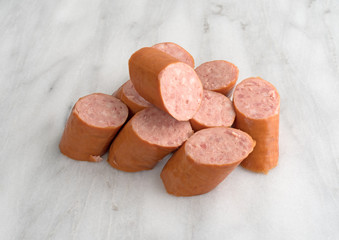 Naklejka premium Slices of Polska Kielbasa on a gray marble cutting board.