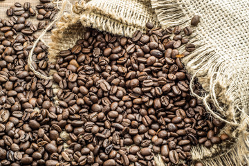 Black coffee beans in burlap sack on wooden table