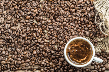 Cup of coffee and coffee beans on wooden table, overhead