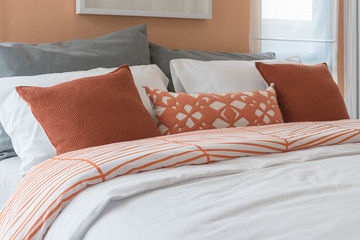 orange color tone pillows set on bed in modern bedroom