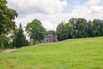 Obraz premium Old farm house historic timbered barn husbandry building green meadow pasture field small rural village