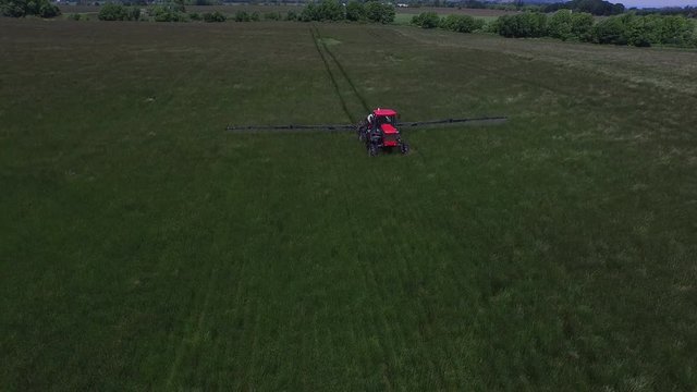 Aerial shot of tractor spraying grass seed farm