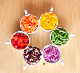 Cut vegetables in white bows arranged in rainbow colors 