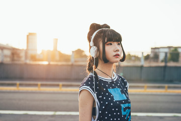 Half length of young beautiful asian millennial woman nonconformist listening music with headphone...