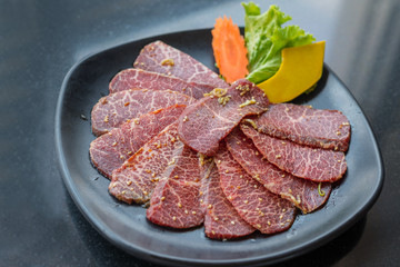 Raw beef slice for barbecue or Japanese style yakiniku on black