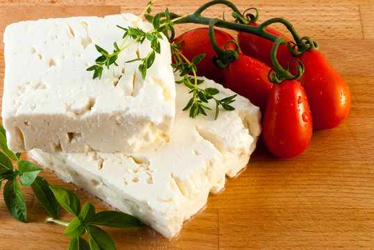 Feta cheese served with fresh tomatos, basil and thyme on wood board