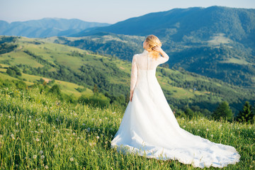 Beautiful bride in a white dress admiring views of the mountains