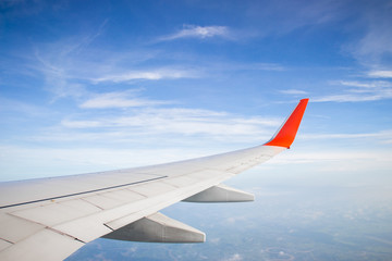 Obraz premium Wing of a plane and blue sky with cloud