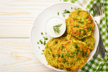 Fritters with zucchini and carrots on white wooden background.