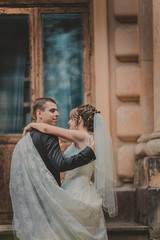 beautiful couple in wedding dress outdoors near the castle columns and old wood doors.