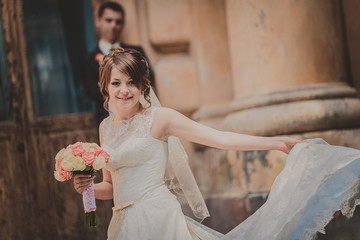 beautiful couple in wedding dress outdoors near the castle columns and old wood doors.