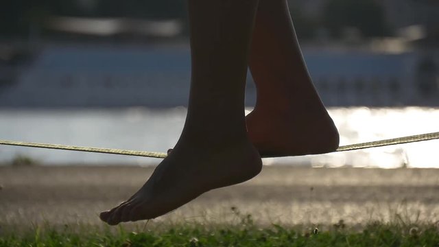 Silhouette of female legs on a slackline rope