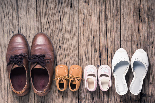 still life photography : father mother son and daughter shoes on old wood floor, family concept