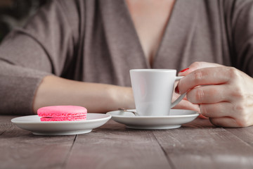 Woman eat macaroon cookies and drink coffee