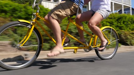 Couple riding tandem bicycle together in coastal vacation community - Powered by Adobe