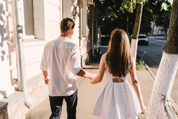 Obraz premium a couple walking in a town together holding hands, look of their backs