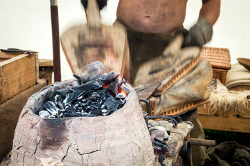 Traditional blacksmith uses bellows to keep a fire