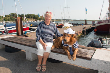 Flotte Seniorin mit Hund in maritimer Kleidung am Hafen von Altefähr Insel Rügen