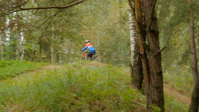 Teen rides a bike through the woods