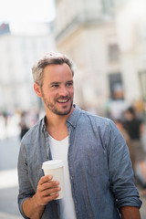 man walking on the streets with a take away coffee at hand