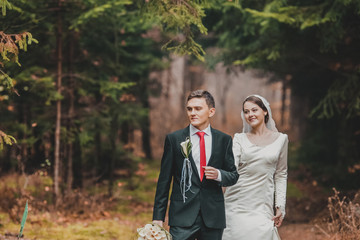 happy bride and groom walking in the autumn forest. Red leaves. 