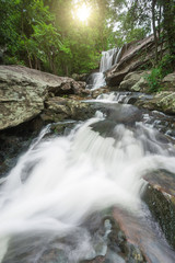 Beautiful waterfall with sun reflection at deep tropical rain forest in Thailand.