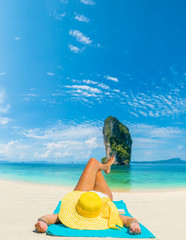 Fototapeta na wymiar Woman lies on the beach with yellow hat