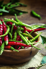 Red and green hot peppers in a wooden bowl. Low key, selective f