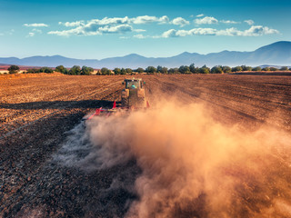 Obraz premium Tractor cultivating field at autumn