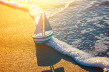 toy sailboat at the seashore during sunset