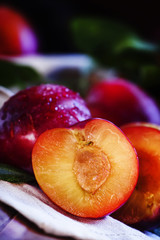 Juicy ripe cut red plum. Vintage wooden background, selective fo