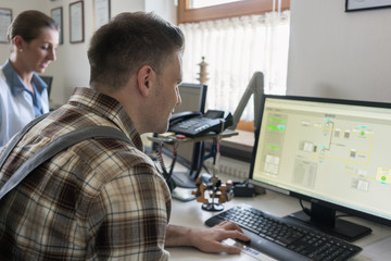 Man and woman in control room of water purification plant monitoring the technical processes