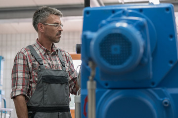 Technician maintaining sewage sludgy dryer in machine room of wastewater treatment plant